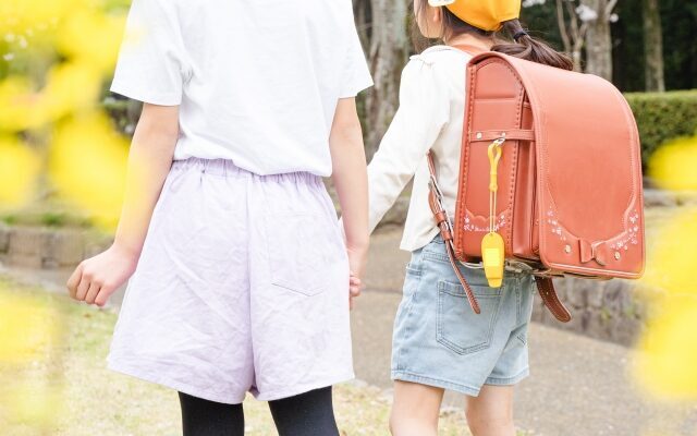 手をつなぐ小学生の後ろ姿